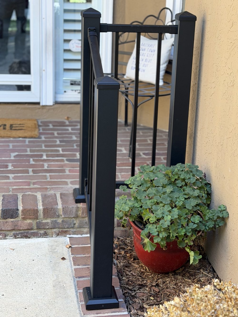 Close-up of a powder-coated handrail post bolted securely to a brick step